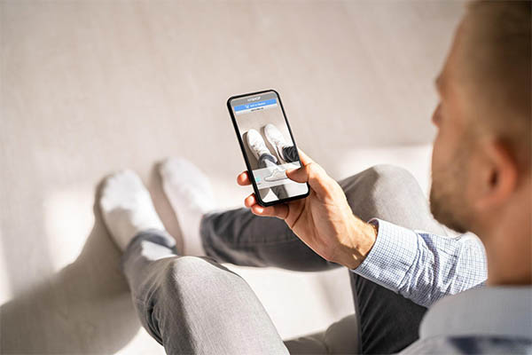 homem usando o celular para provar tenis em realidade aumentada